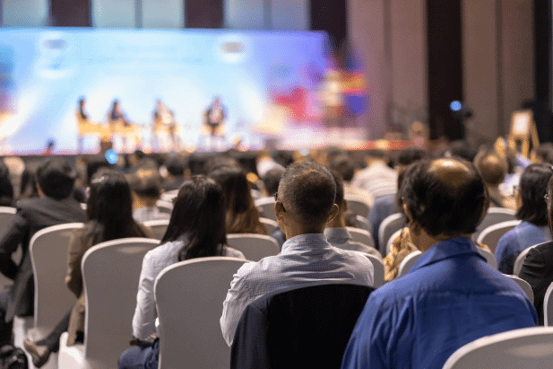 Audience seated facing a panel of speakers on stage at a conference