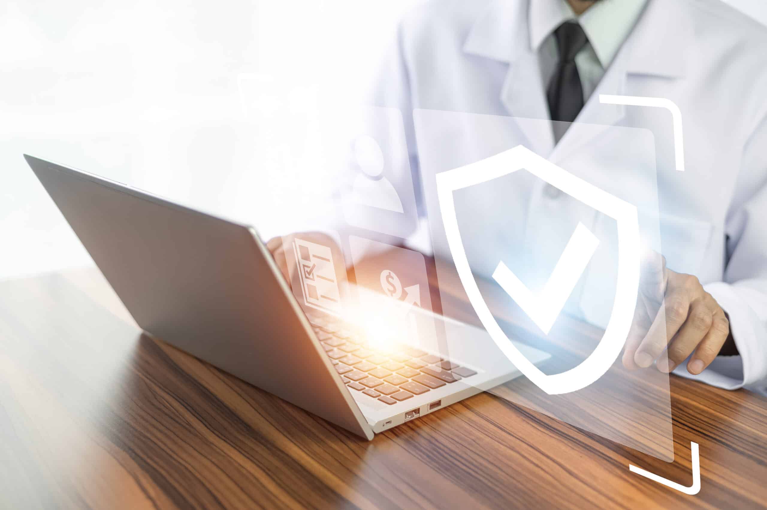 Shield with a checkmark over a laptop, representing secure healthcare claims processing