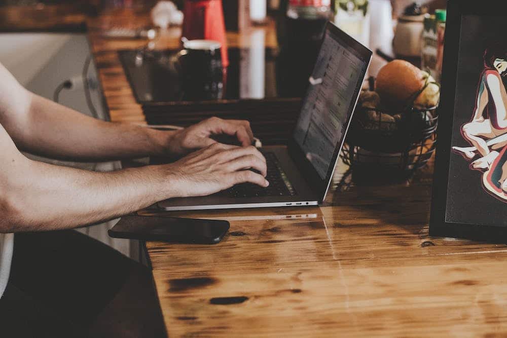 Person typing on a laptop at a wooden desk