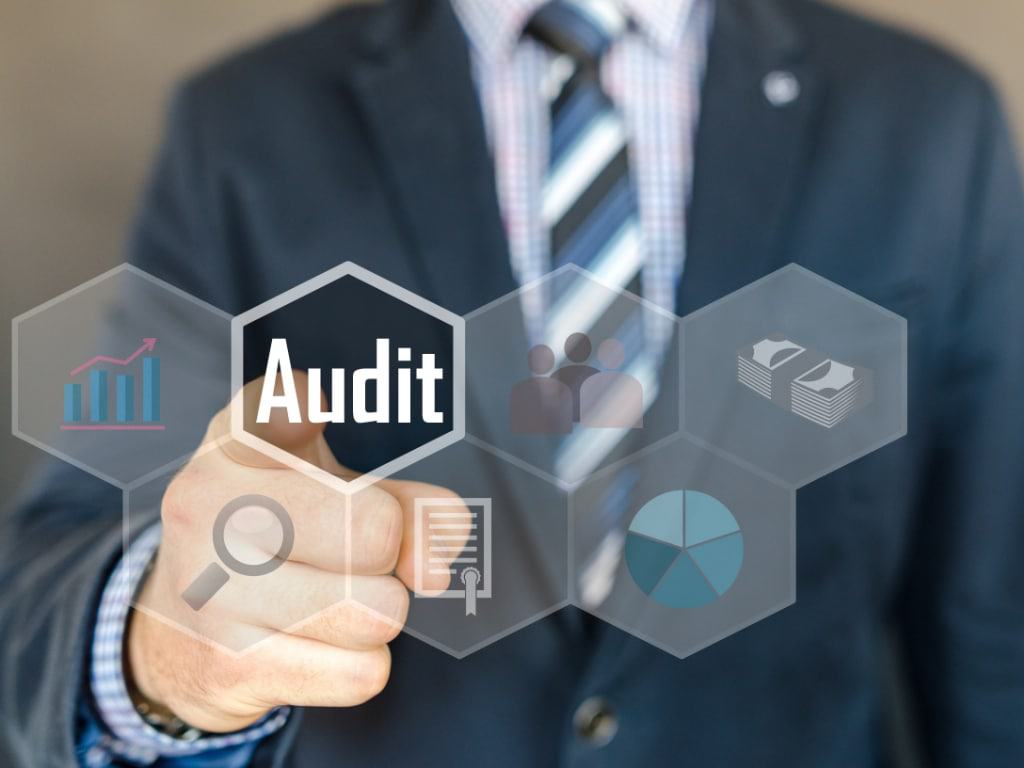 Businessman touching a glowing Audit icon among hexagons for charts, people and documents