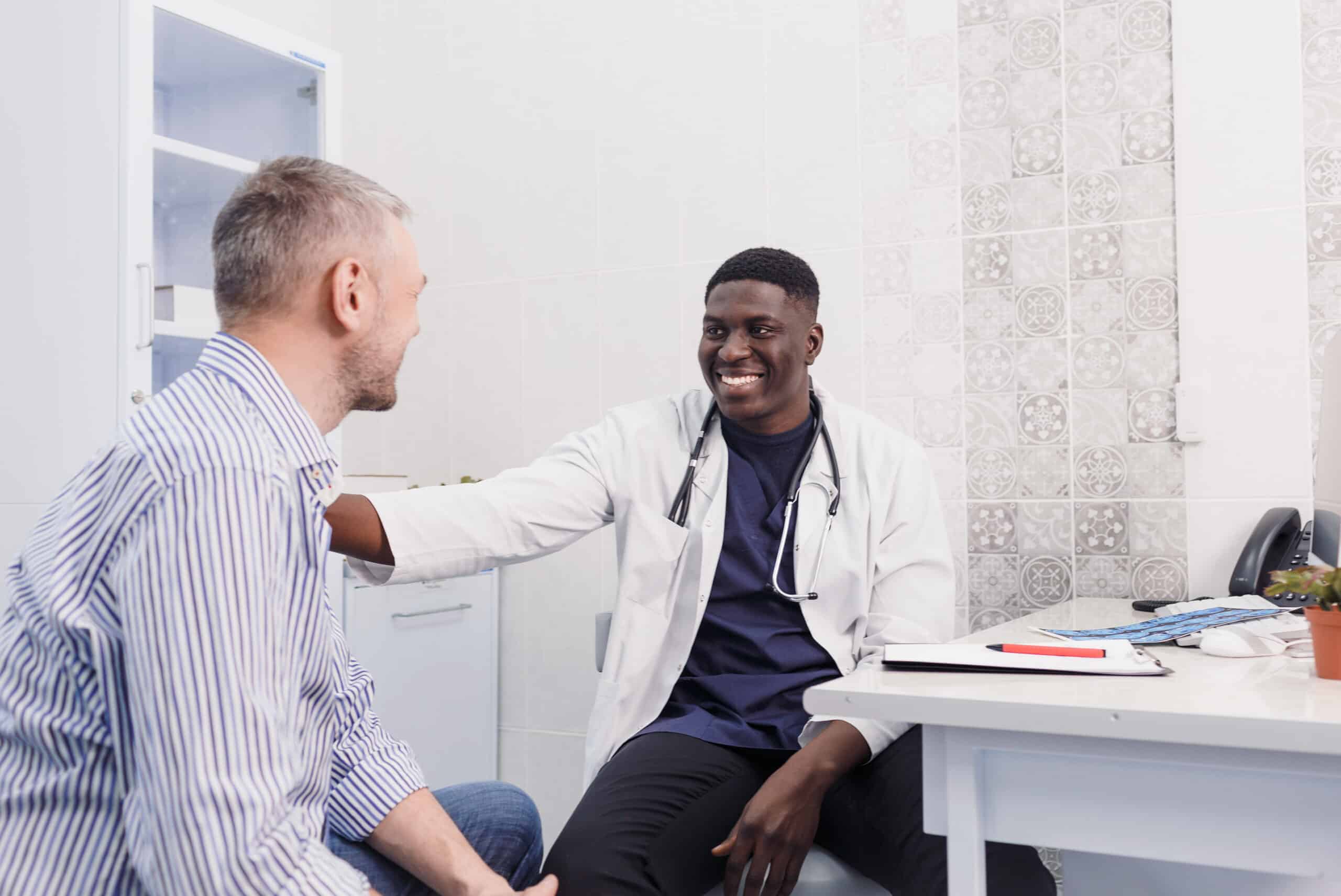 smiling African-American male doctor talks to a patient while sitting at a table